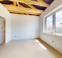 A spacious room in a family house with a beamed ceiling and large windows.