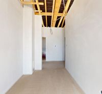 In the family house with a wooden decor floor, there are white walls and an unfinished ceiling.