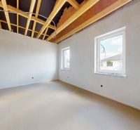 Unplastered walls with an open ceiling and two windows in a family house.