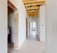 A hallway in an unfinished family house with an exposed ceiling and possible installation.
