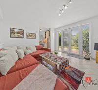 A bright cottage with an orange sofa and carpet, decorated with paintings and accessories.