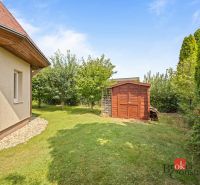 Wooden shelter and grassy garden by the cottage in Vojka nad Dunajom.