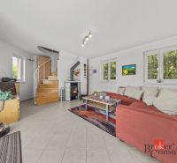A cottage with a comfortable red sofa and a fireplace, complemented by a staircase and decorative elements.