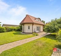 A cottage in Vojka nad Dunajom surrounded by a lawn and trees with a stone pathway.