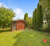 A garden by the cottage in Vojka nad Dunajom with a green lawn and a small wooden house.