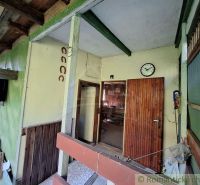 Entrance area of a cabin with a clock on the wall, a door, and an interesting wooden structure.