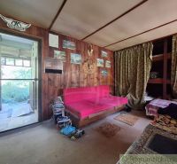 Interior of a cabin with wooden walls, a pink sofa, and decorative curtains.