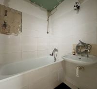 Bathroom in a 3-room apartment with a bathtub and a sink, white tiles on the walls.