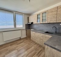 The kitchen of a 3-room apartment with cabinets featuring a wooden decor and large windows.