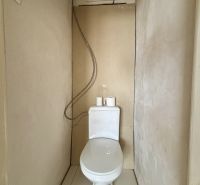 A bathroom in a 3-room apartment with bare walls and a screwed shower hose.