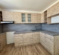 A kitchen with wooden decor and a dark countertop in a 3-room apartment.