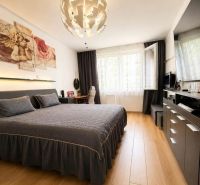 Bedroom in a 2-room apartment with wood-patterned flooring and a stylish chandelier.