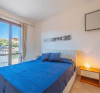 A bedroom in a holiday apartment with a double bed, a window, and a nightstand.