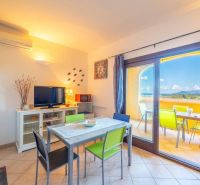Recreational apartment with light flooring, dining table, and view of Sardinia.