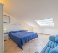 A bright bedroom in a holiday apartment with a double bed and a skylight.