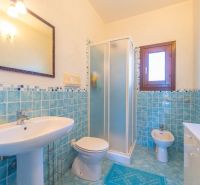 A bathroom in a holiday apartment with blue tiles and a shower enclosure.