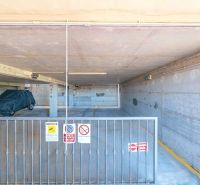 Underground garage of a holiday apartment in Sardinia with a parked car and a security gate.