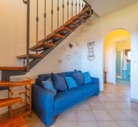 Blue sofa and staircase in a vacation apartment with wood-patterned flooring.