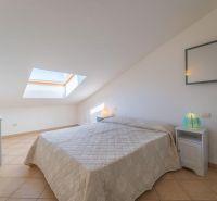 A bright attic bedroom space with a double bed and a skylight.