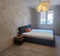 A bedroom with a bed, curtains, and a wooden decor floor in a 3-room apartment.