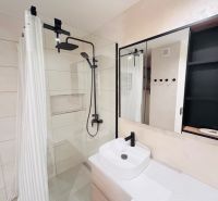 Bathroom with black faucet and shower, mirrored cabinet, modern tiles, 3-room apartment.