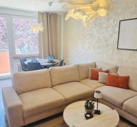 A living room in a three-room apartment with a large sofa and a floor with a wooden decor.