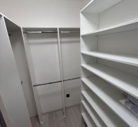Wardrobe with shelves and rods in a 3-room apartment, floor with wood decor.