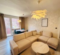 A room in a 3-room apartment with a sofa, a round table, and a floor with a wood decor.