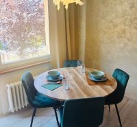 Dining area in a 3-room apartment with a round table and green chairs.