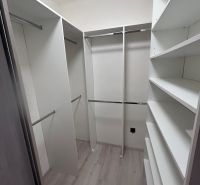 A wardrobe in a 3-room apartment with shelves and storage spaces, flooring with a wood decor.