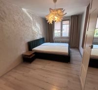 Bedroom in a 3-room apartment with a wooden decor floor and a stylish light fixture.