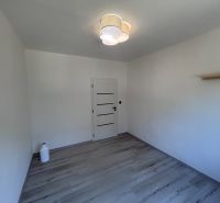 A room with a wooden decor floor and white walls in a 3-room apartment.