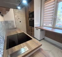 A kitchen with built-in appliances and a wooden decor floor in a 3-room apartment.