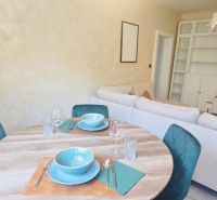 A dining table with place settings, behind it a sofa and a bookcase in a 3-room apartment.