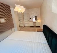 A bright bedroom in a three-room apartment with a wooden decor floor and a wardrobe.