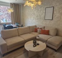 Comfortable sofa, dining table, wooden decor flooring in a 3-room apartment.