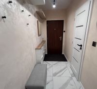 A hallway with light tiles and a bench in a 3-room apartment.