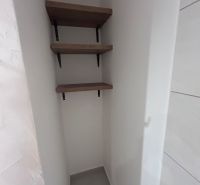A narrow corner with three shelves in a 3-room apartment.