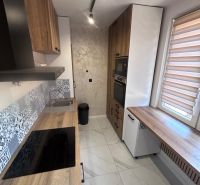 A kitchen with a wood-patterned floor, furnishings, and modern appliances in a 3-room apartment.