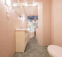 A bathroom with a bathtub and tiles in a 3-room apartment, light tones and a large mirror.