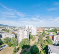 A view of the city of Nitra with 3-bedroom apartments and greenery under a blue sky.
