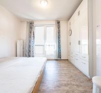 A bright bedroom in a 3-room apartment with a wooden decor floor and a built-in wardrobe.