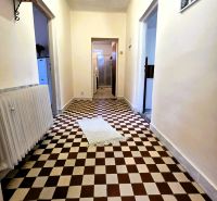 A hallway in a family house with checkered tiles and a white rug in the center.