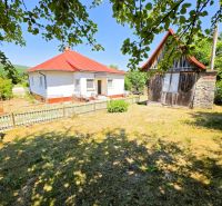 A family house in Slanská Huta with a red roof, a garden, and a wooden fence.