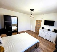A bedroom in a family house with a wooden decor floor and a TV on the wall.