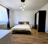 Bedroom in a family house with a bed, wardrobe, and wooden decor flooring.