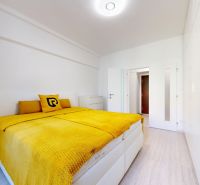Bedroom in a 2-room apartment with a bed and white furniture, floor with wooden decor.