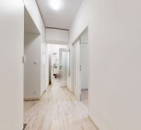 A bright hallway with white walls and a wooden decor floor in a 2-room apartment.