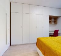 A bedroom in a two-room apartment with white wardrobes and a yellow bedspread.
