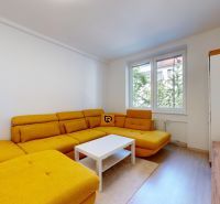 Living room with a yellow sofa, white coffee table, and wood-patterned flooring.